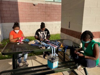 Young women sit around a picnic table working on a craft